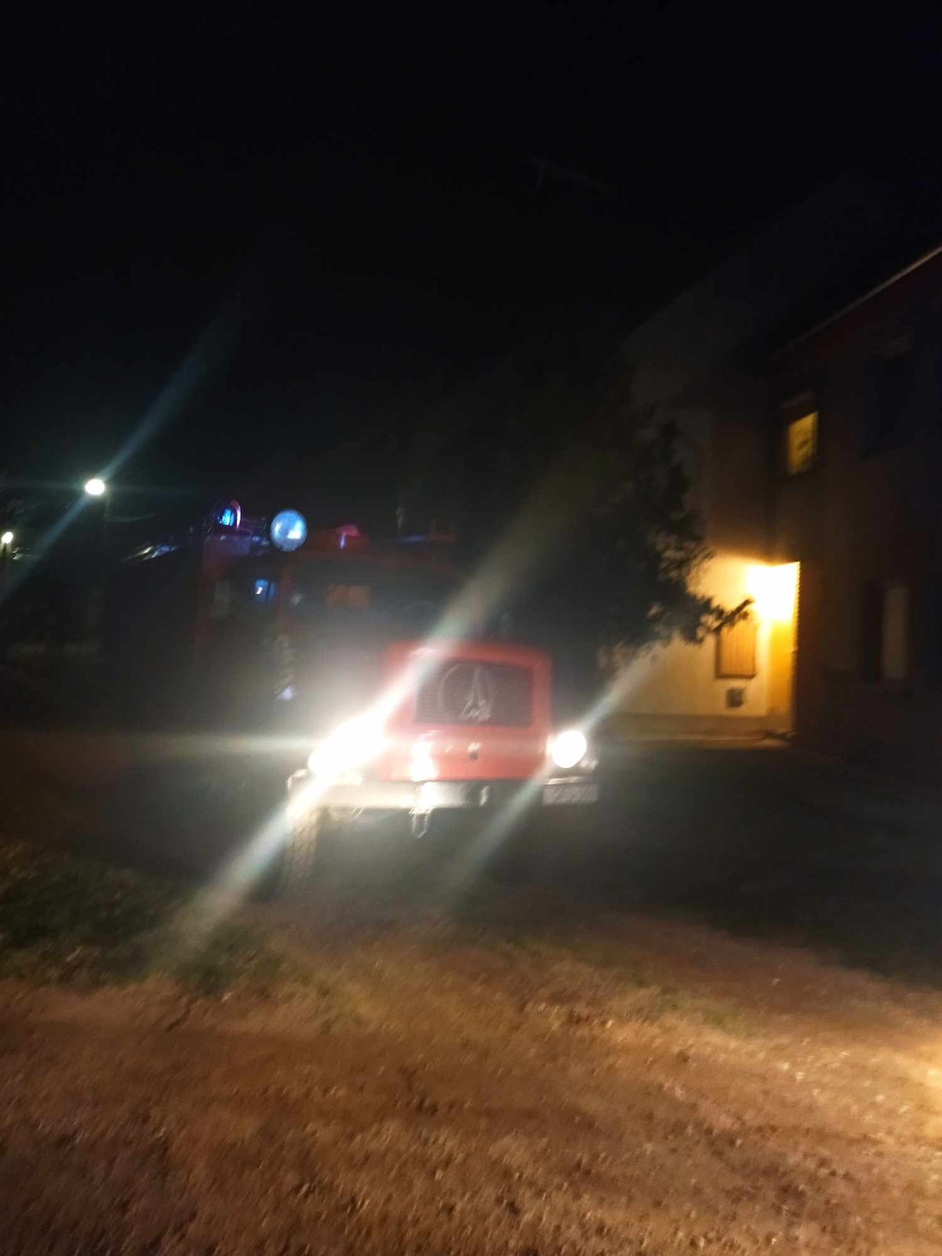 Éjszakai vonulás: a tűzoltóautó fényszórói egy tanyasi úton.